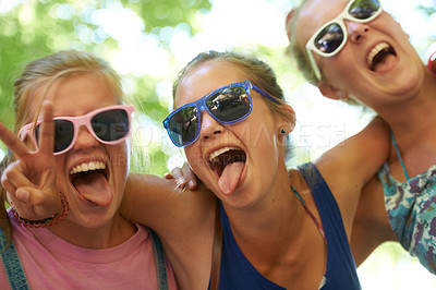 Buy stock photo Portrait, music festival and women with sunglasses, funny and silly with happiness and bonding together. Funky eyewear, goofy or outdoor with friends or peace sign with embrace, excited or summer fun