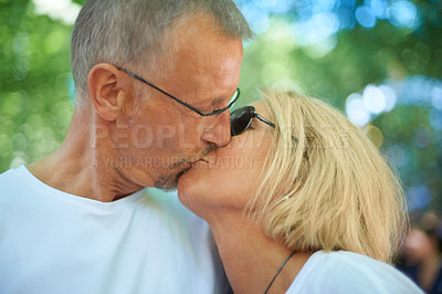Buy stock photo Senior couple, kiss and love in outdoor in nature, happy and bonding together in forest. Mature man, woman and romantic at summer adventure for celebration and care on retirement holiday in europe