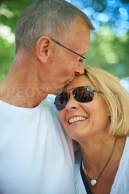 Buy stock photo Senior couple, kiss and care in outdoor in nature, happy and bonding together in forest. Mature man, woman and romantic at summer adventure for celebration and love on forehead for europe holiday