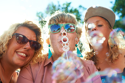 Buy stock photo Women, friends and bubbles for blowing outdoor with sunglasses on weekend, break or holiday for relax and summer. People, happy and plastic wand or toy for playing or leisure on vacation or adventure