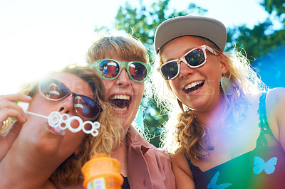 Buy stock photo Women, friends and bubbles for blowing or fun outdoor with sunglasses on weekend, break and holiday for relax. People, happy and plastic wand or toy for playing or laughing with vacation or adventure