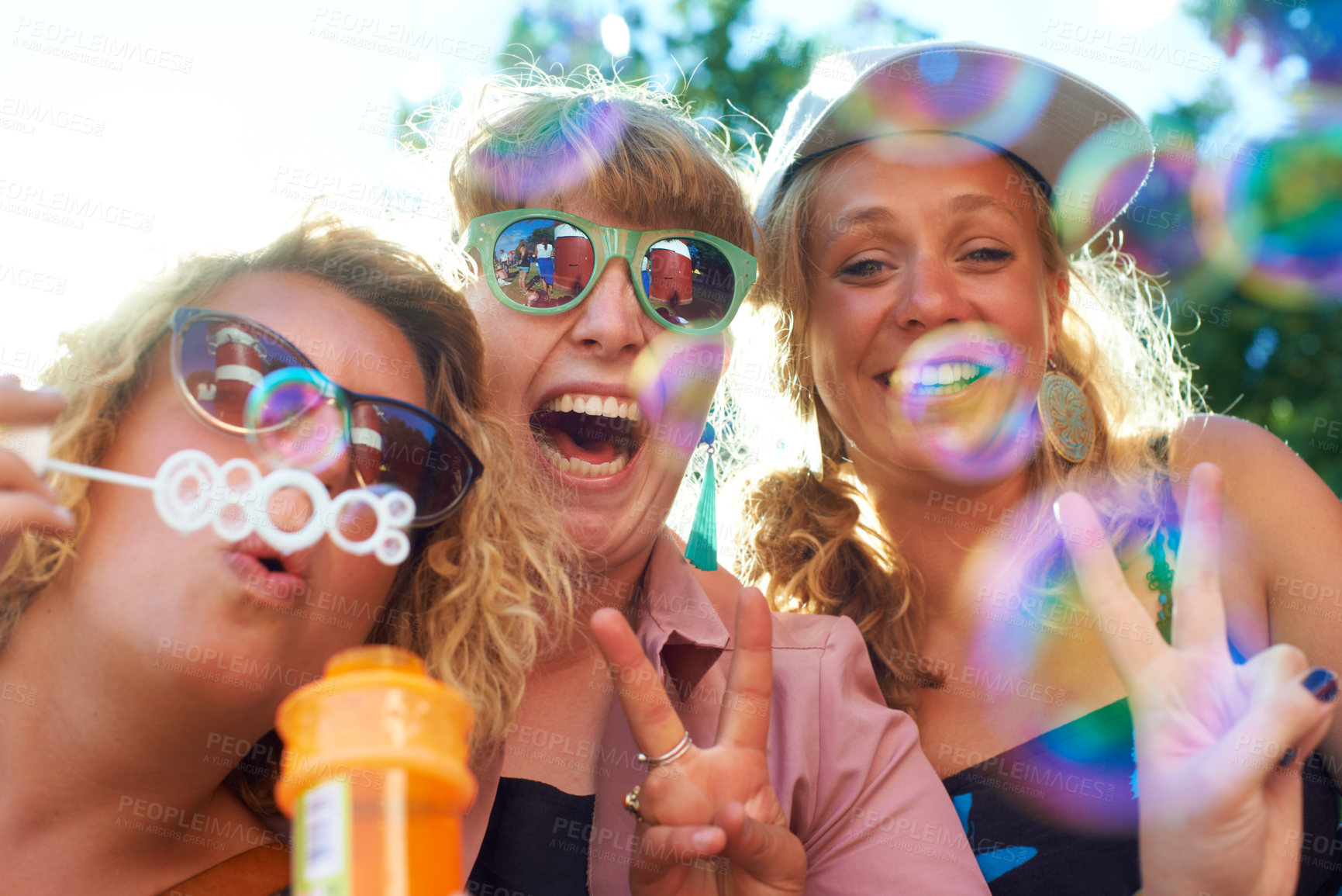 Buy stock photo Women, friends and bubbles for blowing or happy outdoor with sunglasses or peace sign for holiday and relax. People, face and plastic wand or toy for playing and laughing with vacation or adventure