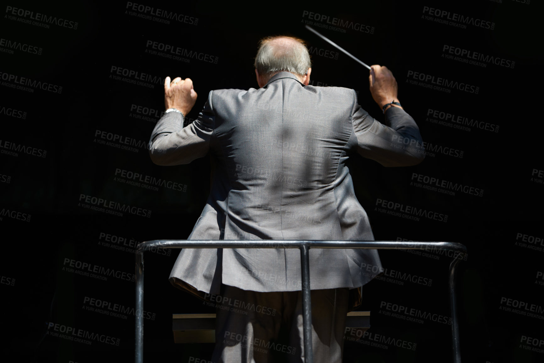 Buy stock photo Cropped rear view of an orchestra conductor waving his baton