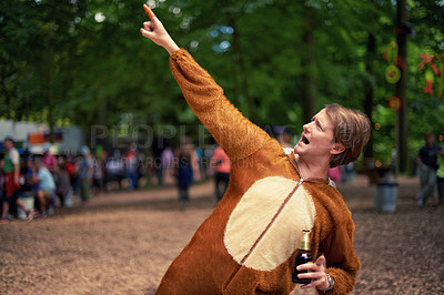 Buy stock photo Halloween, costume and man with beer to drink at happy celebration outdoor in bear outfit. Animal, suit and person pointing to trees with lager, bottle and drinking alcohol in park at festival