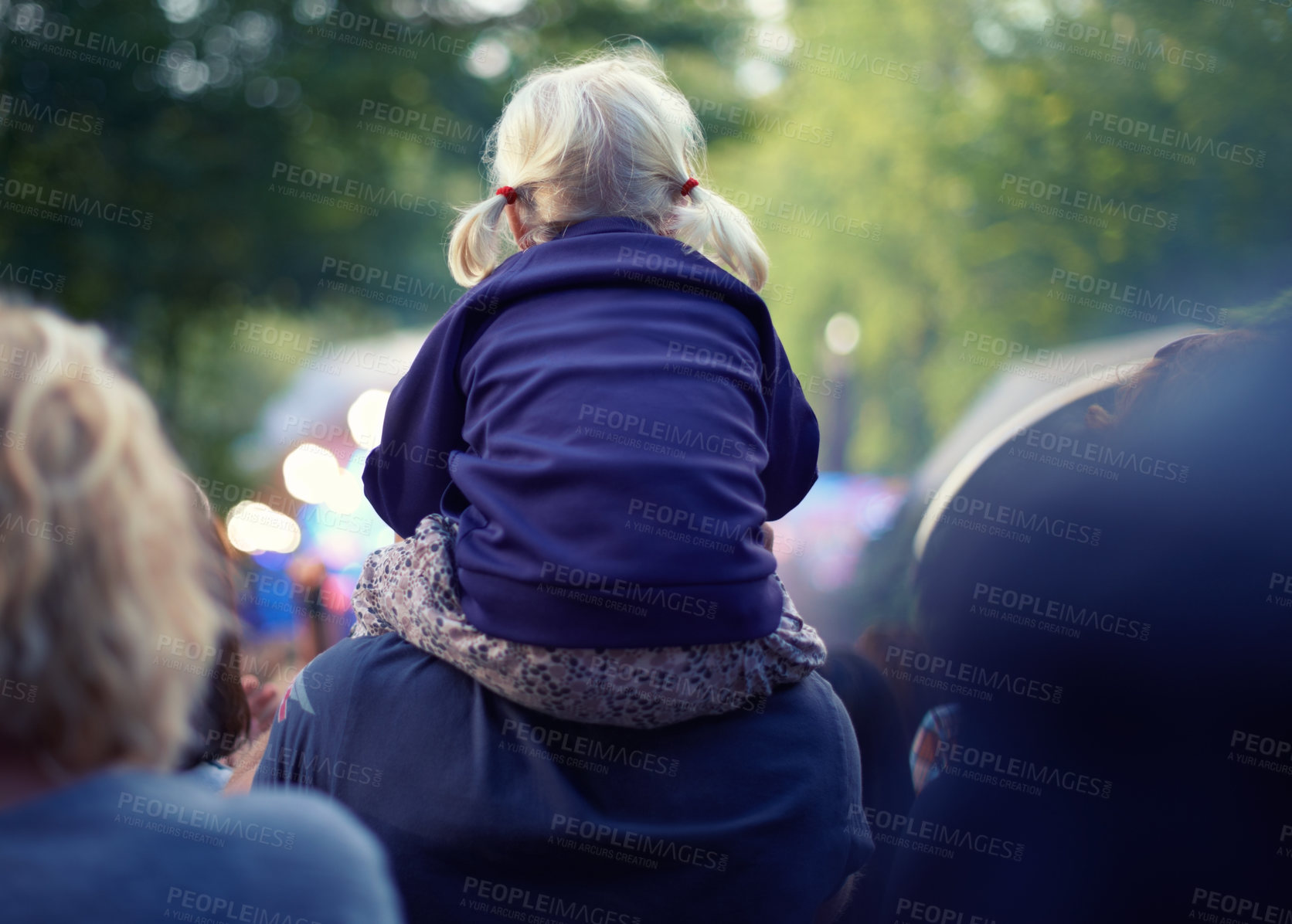 Buy stock photo A little girl sitting on her father's shoulders at an outdoor event