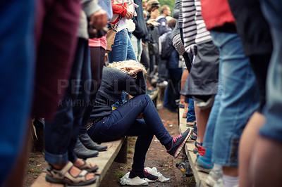 Buy stock photo Woman, sad and alone in crowd while sitting outside at festival, protest or concert in Poland. Female supporter, exhausted or overwhelmed during outdoor fundraising event during spring or autumn