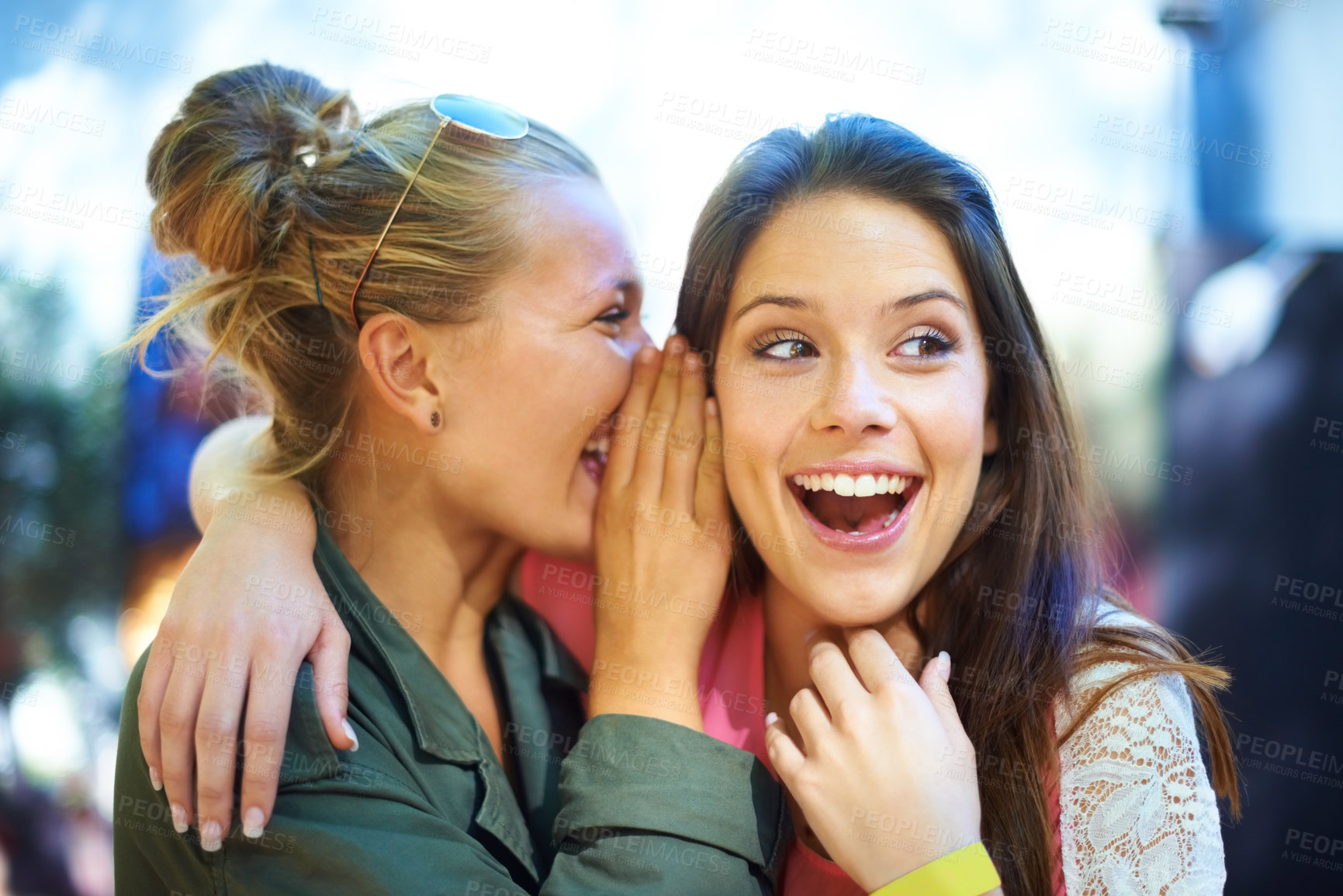 Buy stock photo A young woman whispering a secret in her friend's ear