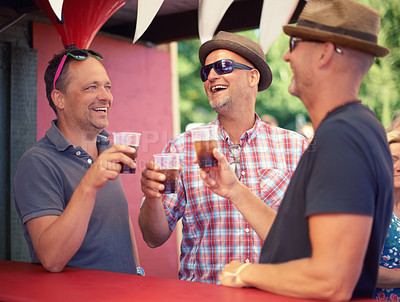 Buy stock photo Cropped shot of three male friends drinking at a festival