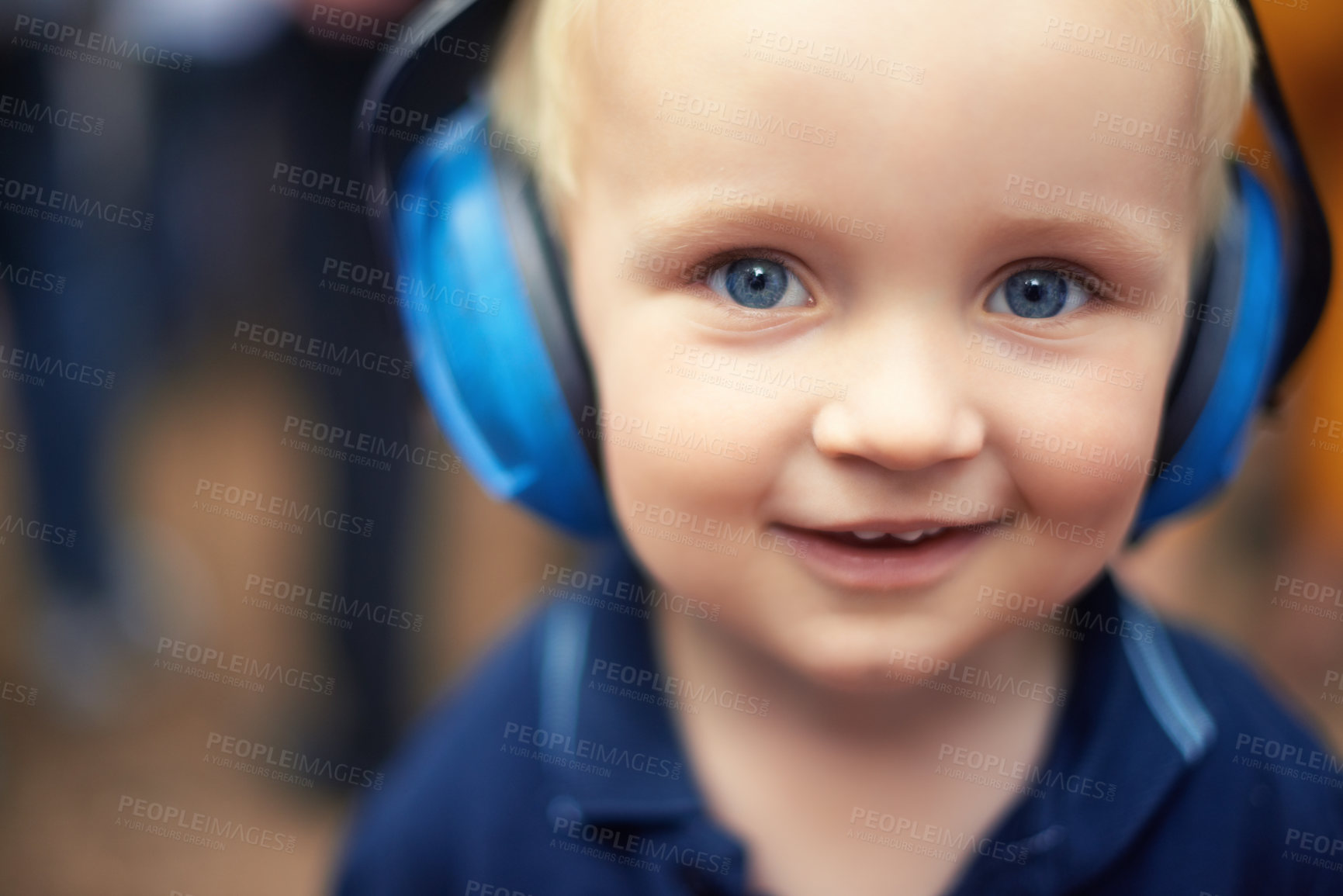 Buy stock photo Baby, closeup and smile for portrait with headphones for noise at outdoor festival, happy and cute kid. Natural, blue and eyes with zoom face, toddler and innocent alone at concert for fun time