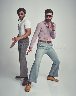 Buy stock photo Studio shot of two men standing together while wearing retro 70s wear and striking a pose