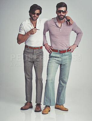Buy stock photo Studio shot of two men standing together while wearing retro 70s wear and smoking pipes