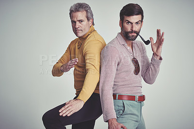 Buy stock photo Studio shot of two men standing together while wearing retro 70s wear and striking a fighting pose