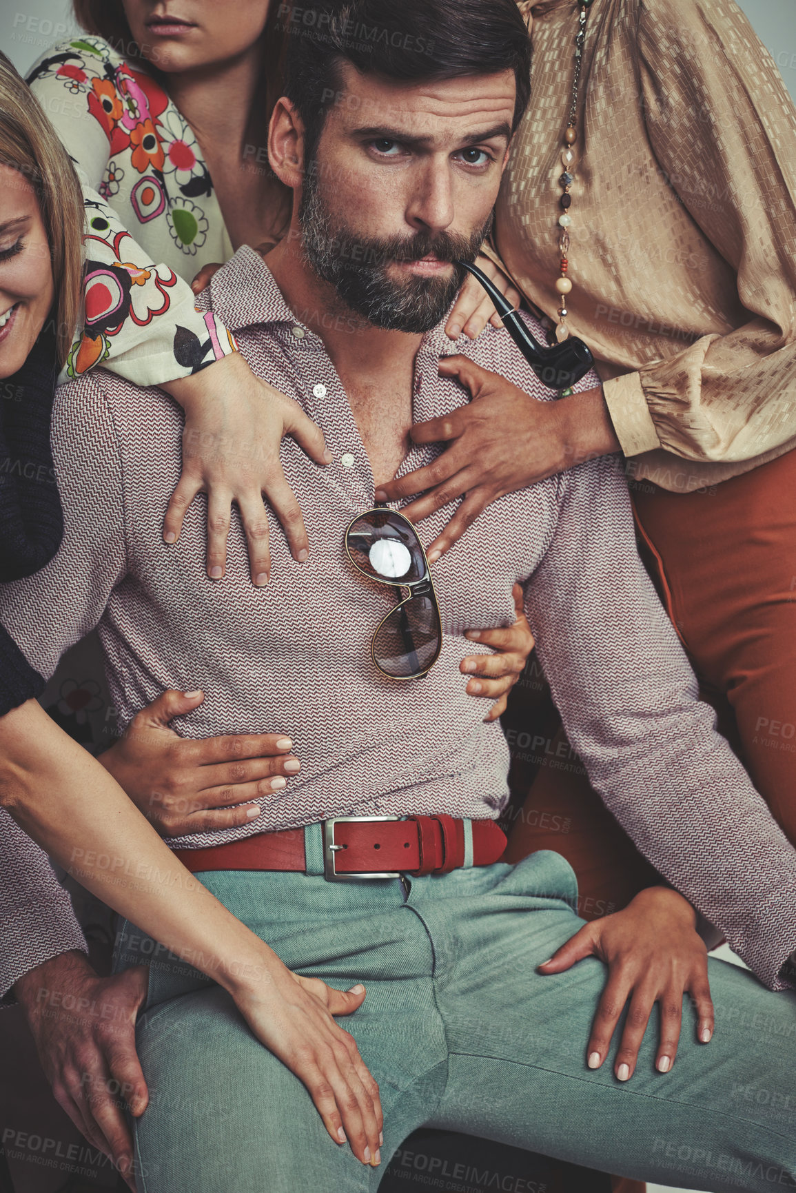 Buy stock photo Studio shot of an attractive man in retro 70s wear surrounded and being touched by women