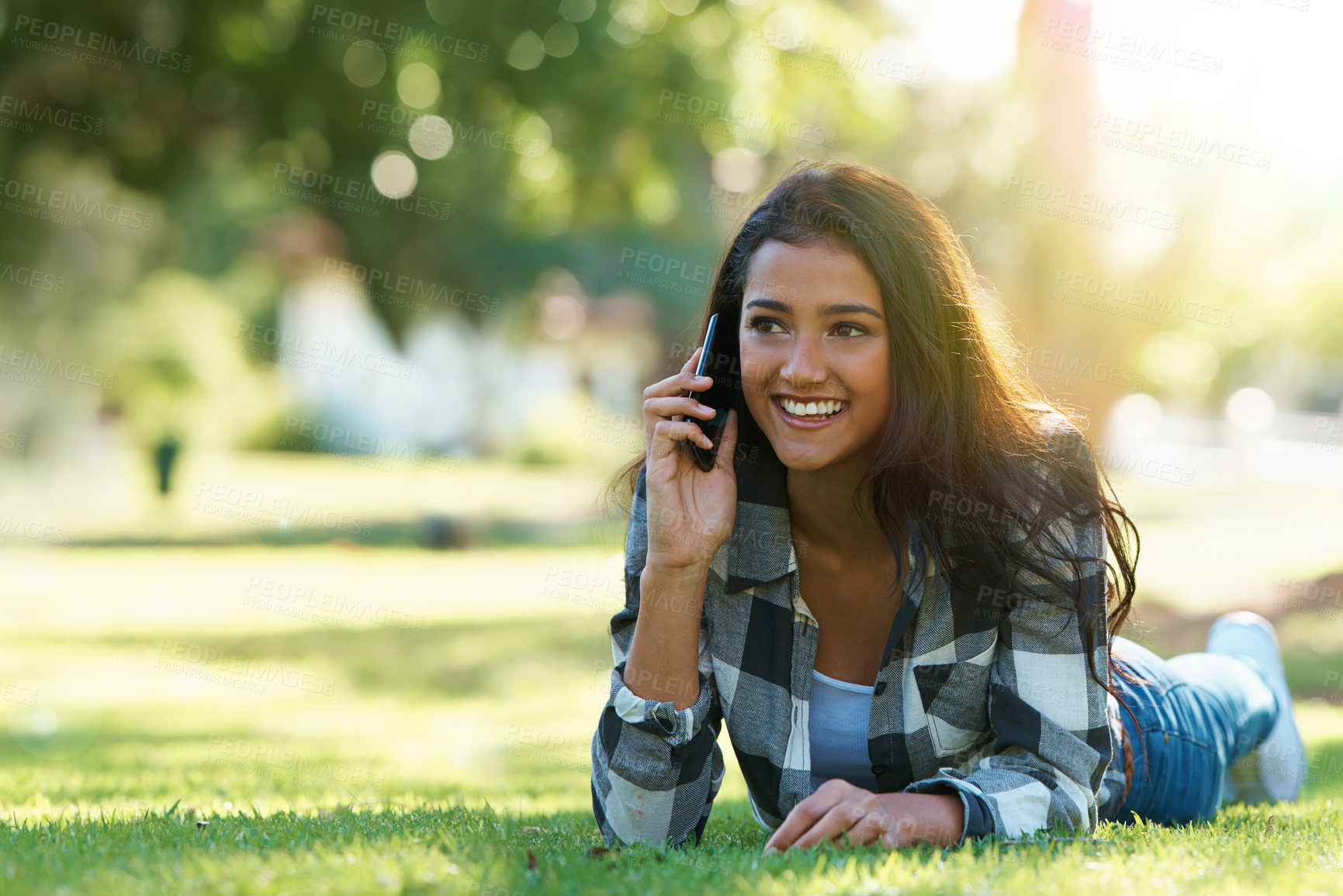 Buy stock photo Shot of an attractive young woman talking on the phone in a park