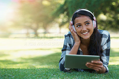 Buy stock photo Woman, headphones and streaming podcast on tablet, learning and internet for education on grass in outdoors. Female person, happy and relaxing on lawn, knowledge and student subscription for info