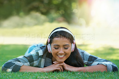 Buy stock photo Woman, headphones and streaming song on grass, peace and calming podcast in outdoors. Female person, happy and relaxing on lawn, weekend playlist and subscription for audio or sound on vacation