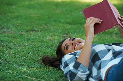 Buy stock photo Happy woman, student and lying with book on green grass for literature, studying or story in nature. Female person, bookworm or young adult with smile and notebook for reading or education at park