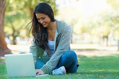 Buy stock photo A young woman working on her laptop in a park
