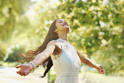 Buy stock photo A carefree woman standing with her arms open in the park