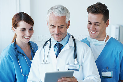 Buy stock photo Three medical professionals discussing information presented on a digital tablet