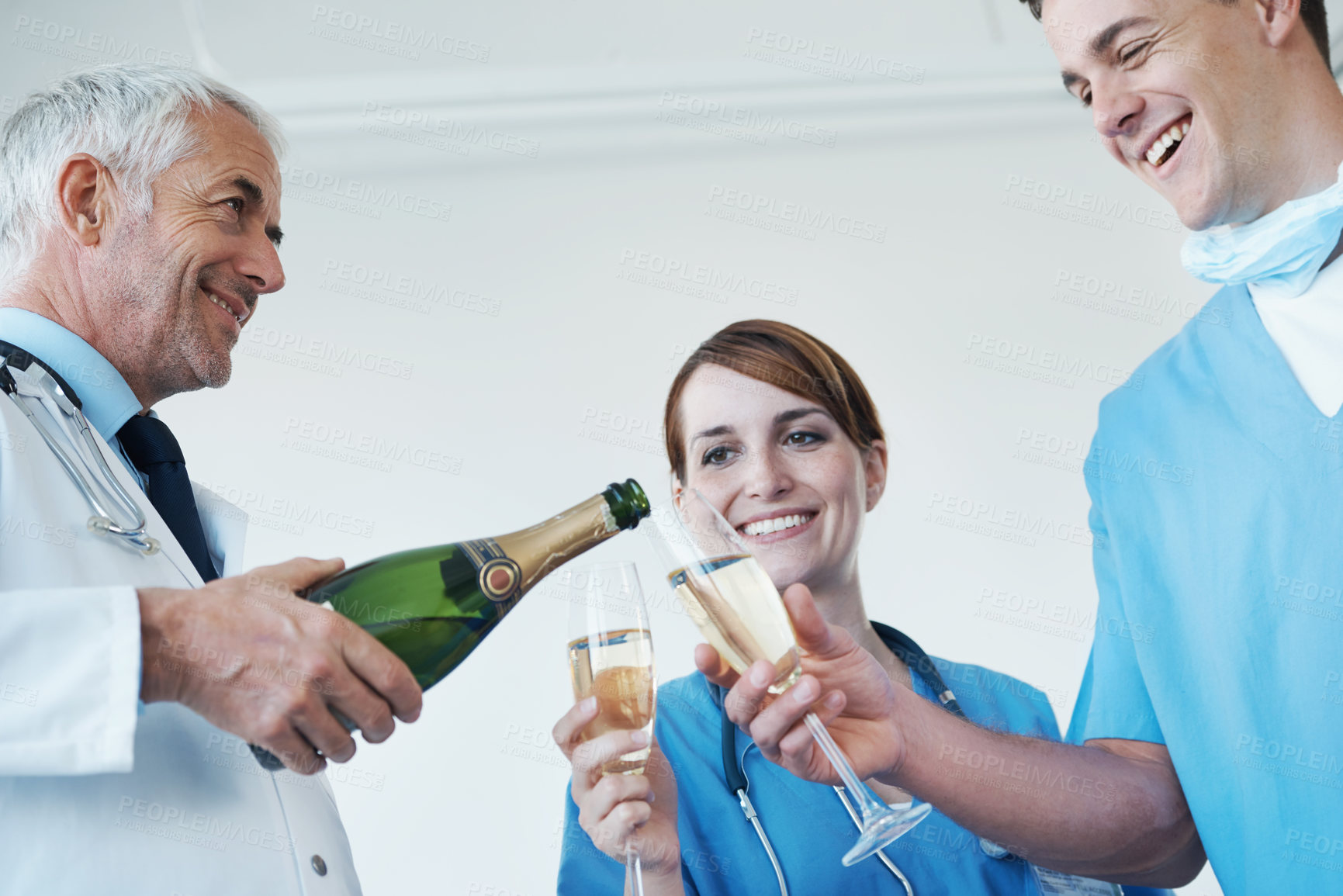 Buy stock photo A general practitioner, nurse and surgeon drinking champagne together after a successful procedure