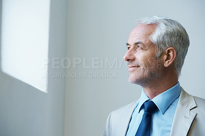 Buy stock photo Shot of a thoughtful-looking mature businessman looking out of a window