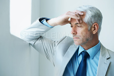 Buy stock photo Shot of a stressed-out looking mature businessman leaning against a wall