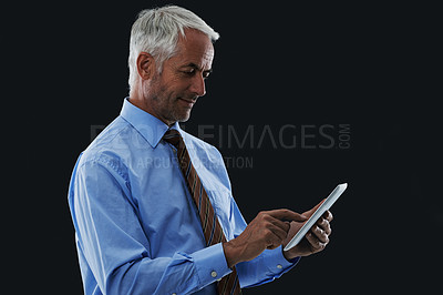 Buy stock photo Businessman, tablet and typing in studio for research, communication or networking with clients online. Male CEO, technology and scrolling for information, planning or working on black background