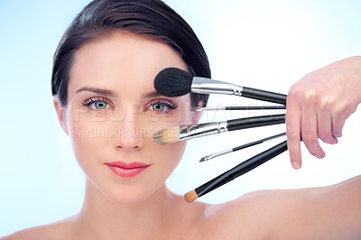 Buy stock photo A beautiful young woman holding a variety of make-up brushes