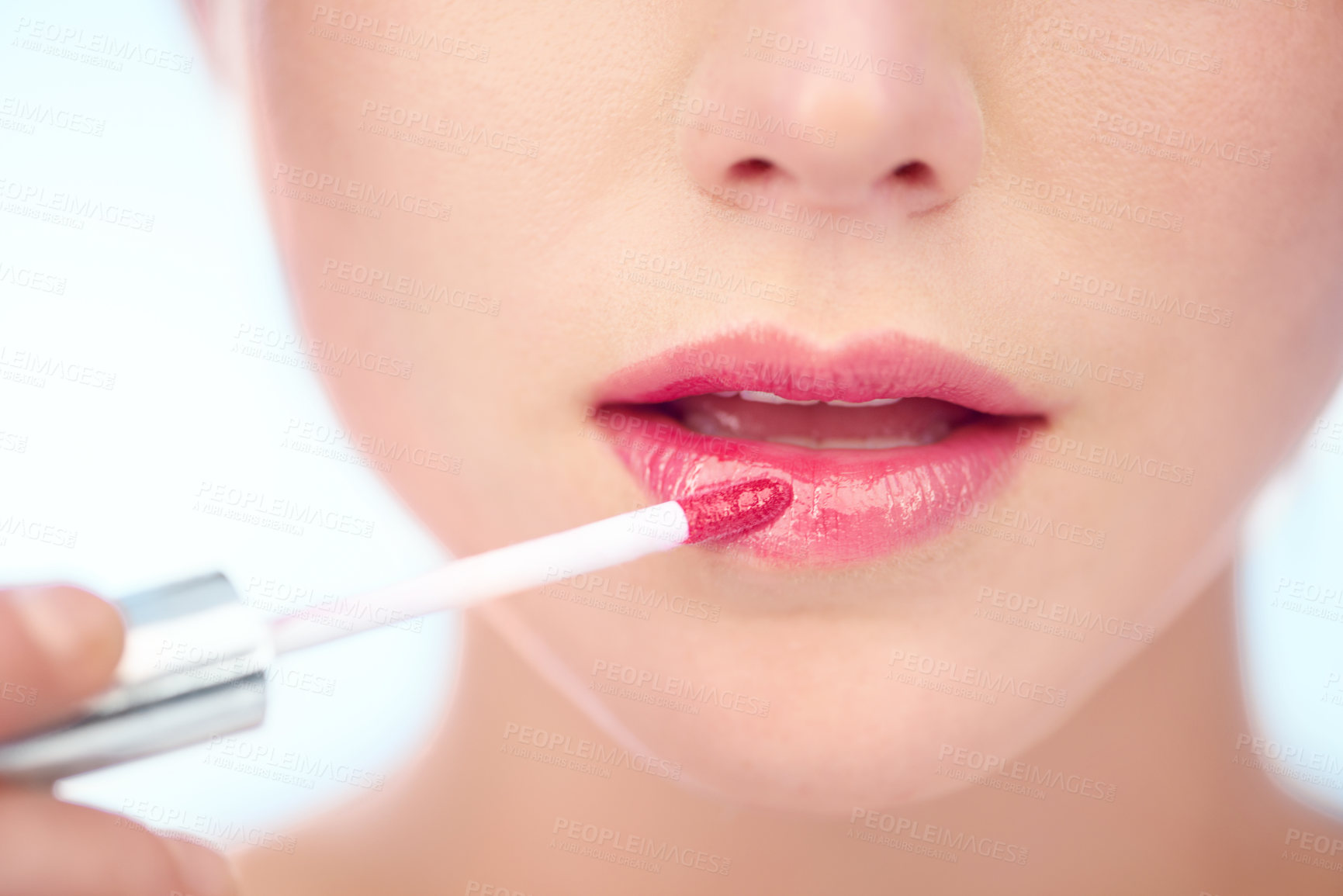 Buy stock photo A young woman applying pink lipstick with an applicator