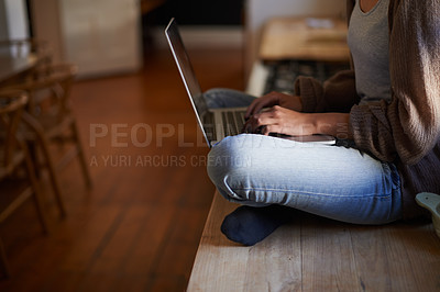 Buy stock photo Cropped image of a woman sitting on a counter typing on her laptop