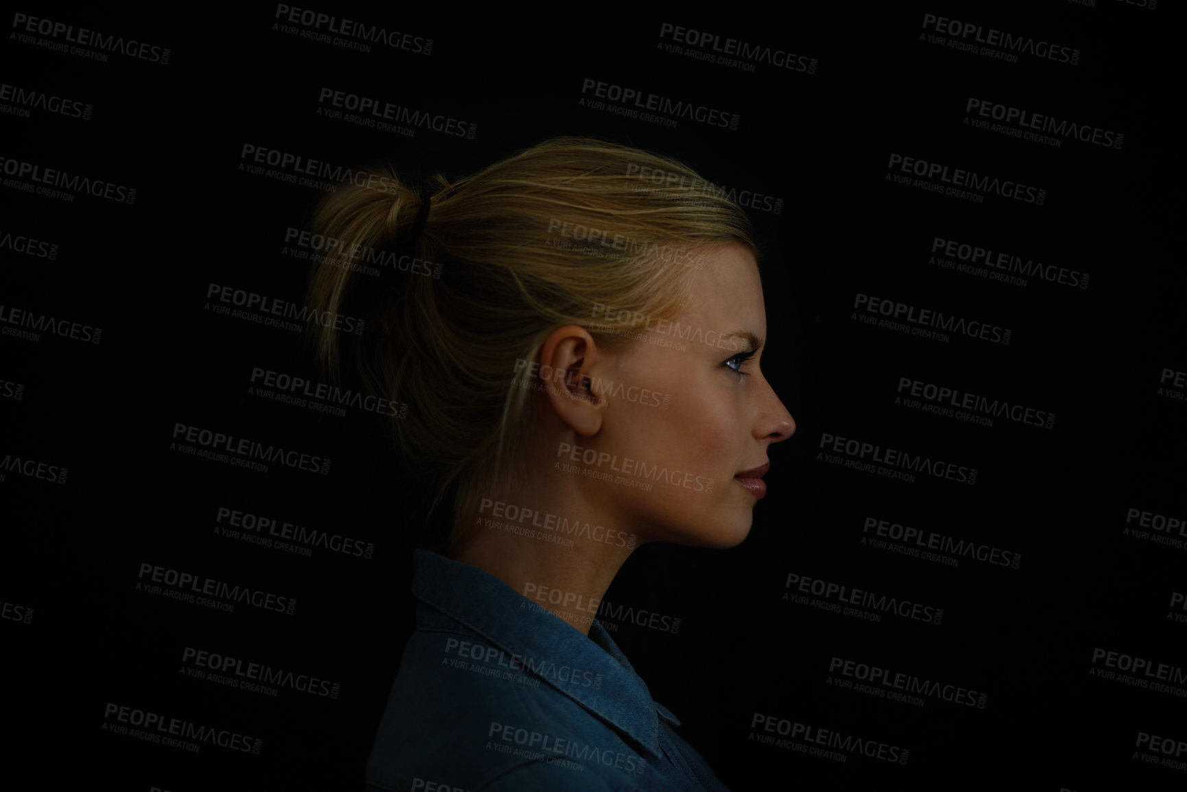Buy stock photo A young woman in a denim shirt against a dark background