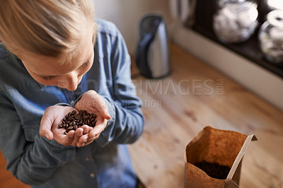 Buy stock photo A young woman smelling fresh coffee beans in her kitchen