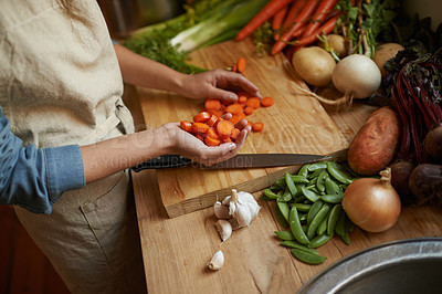 Buy stock photo Hands, vegetables and cutting carrots for cooking in kitchen with onion or potato, leafy green or nutrition. Person, knife and garlic on counter for healthy wellness or salad diet, vegan or fibre