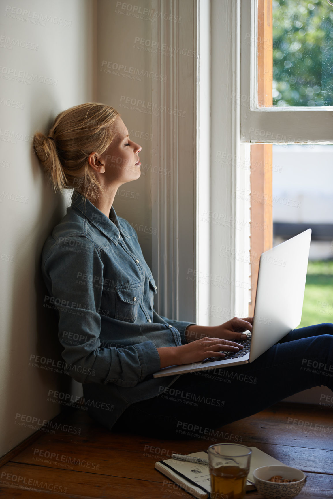 Buy stock photo Woman, freelancer and laptop by window, writer and internet connection on floor for info. Female person, editor and website for research or online news, blogging and typing an article on technology