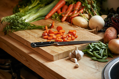 Buy stock photo Vegetables, carrots and wood board for cooking in kitchen with onion or potato, leafy green or nutrition. Knife, garlic and counter for healthy wellness or salad diet for vegan dish, fibre or recipe