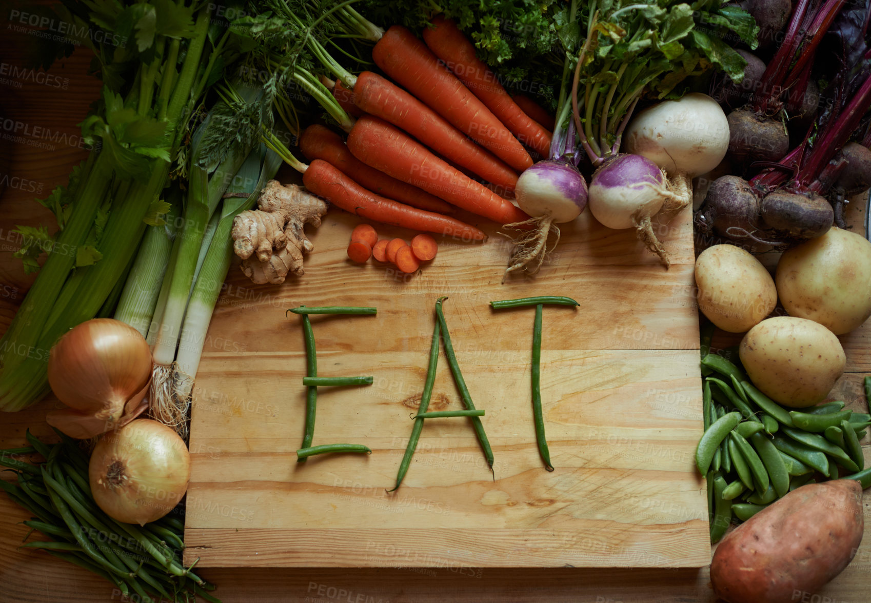 Buy stock photo Vegetables, chopping board and kitchen with variety ingredients with the message 'eat'. High angle, fresh from the earth and healthy green foods, herbs or organic produce harvest on wooden piece 