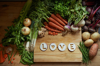 Buy stock photo Food, chopping board and message for love, nutrition and cooking for wellbeing or eating. Home, above and vegetables for diet, health and vitamins in kitchen for vegan, vitality and top view
