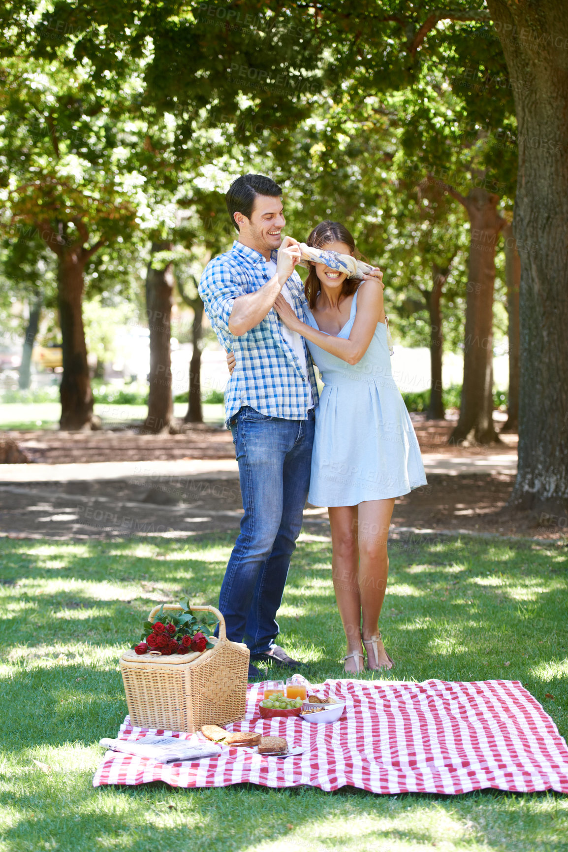 Buy stock photo Love, picnic and surprise with couple in park for romance, bonding and summer vacation. Happiness, commitment and relax with man and blindfold woman in nature for date, support and relationship