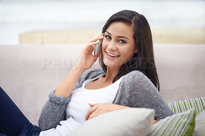 Buy stock photo Shot of a young woman sitting on a sofa and talking on the phone