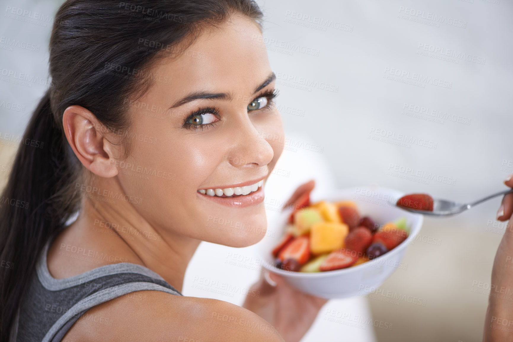 Buy stock photo A young woman eating a bowl of chopped fruit