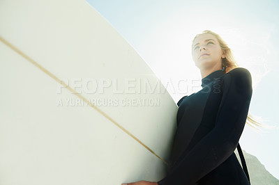 Buy stock photo Face, flare and woman on beach with surfboard from below for travel, vacation or adventure on coast in summer. Nature, fitness or exercise with confident young surfer person in wetsuit for recreation