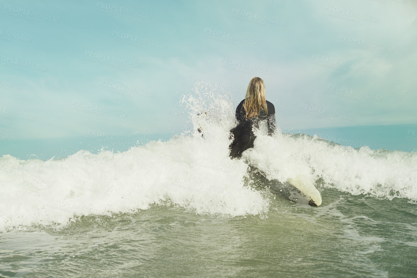 Buy stock photo Ocean, wave and splash with surfer woman in wetsuit for sports, fitness or exercise in summer from back. Blue sky, sea and surfing with person on surfboard in water for travel, vacation or holiday