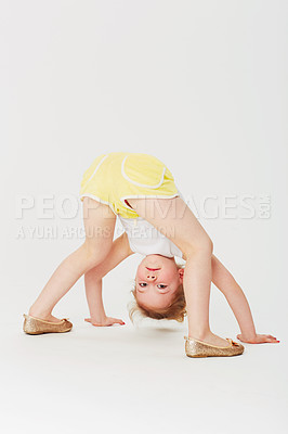 Buy stock photo Studio portrait of an adorable little girl bending double and looking at the world upside down