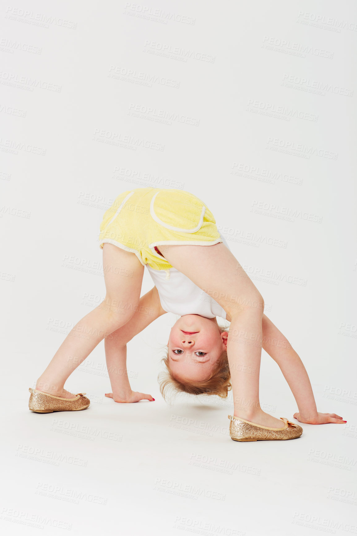 Buy stock photo Studio portrait of an adorable little girl bending double and looking at the world upside down