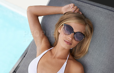 Buy stock photo Shot of an attractive blonde woman lying by a pool