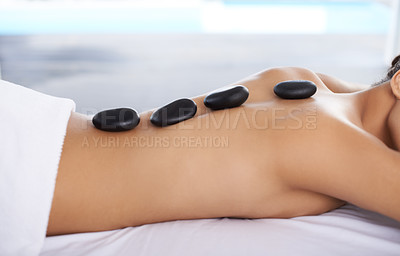 Buy stock photo Shot o a young woman getting a hot rock treatment at a spa