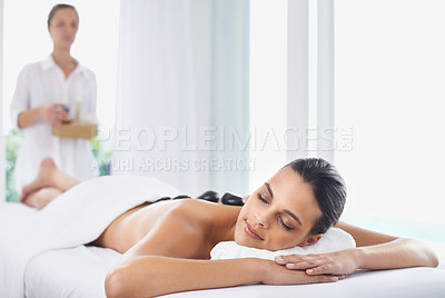 Buy stock photo Hot stone, massage and woman at spa to relax, beauty and pamper back for wellness at luxury salon. Therapist, rocks and person in treatment for skincare, peace or calm for healthy body with masseuse