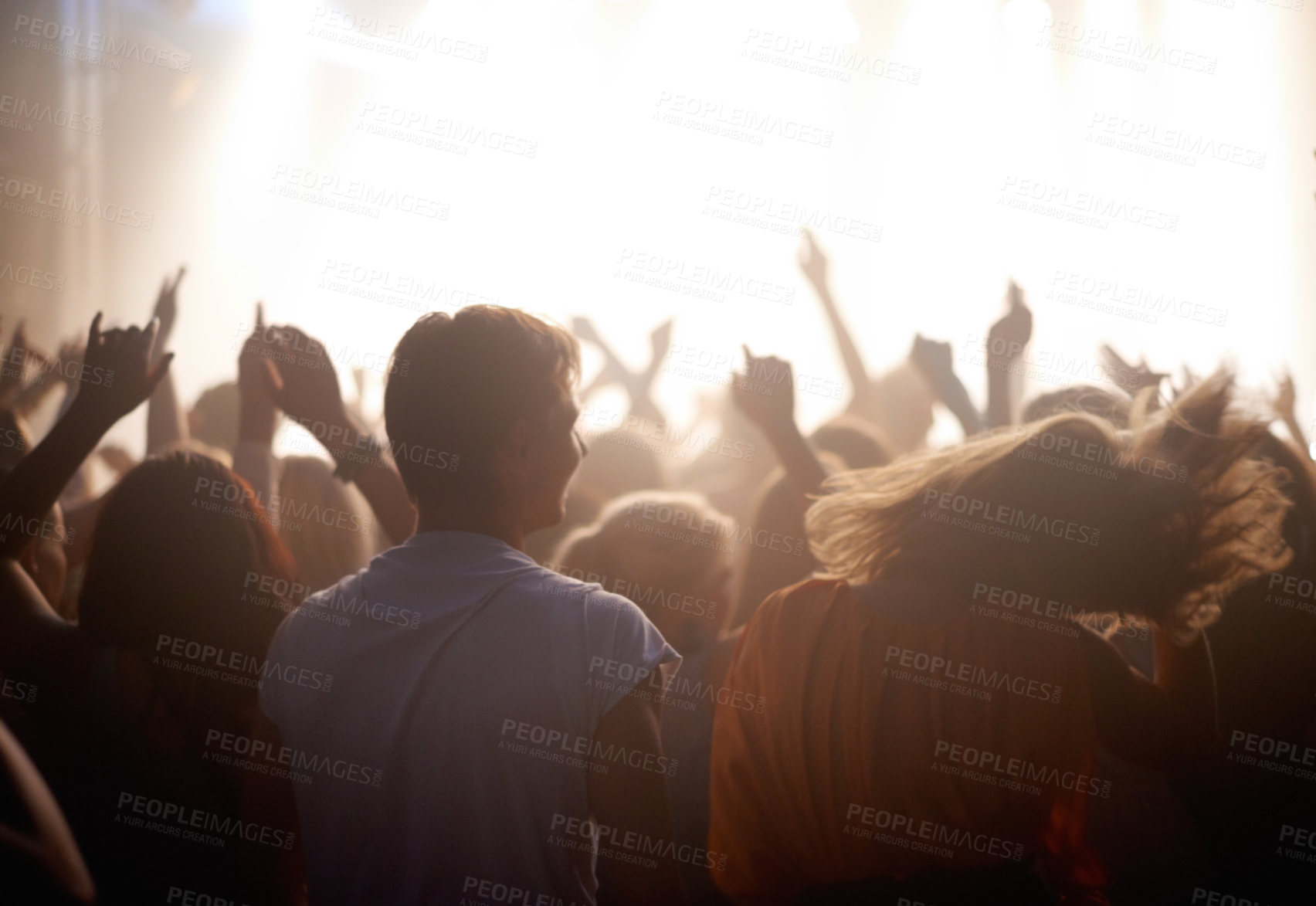 Buy stock photo Fans, people dancing at music festival from back, stage light and energy at live concert event. Dance, fun and excited crowd in arena at rock band performance or audience at show or techno rave party