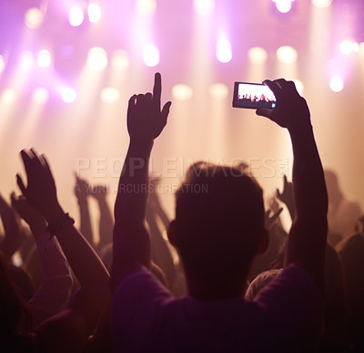 Buy stock photo Fan, phone filming and band on stage with excited audience, lighting colors and music performance on video. Smartphone screen, photography and festival crowd at night and concert, event or party